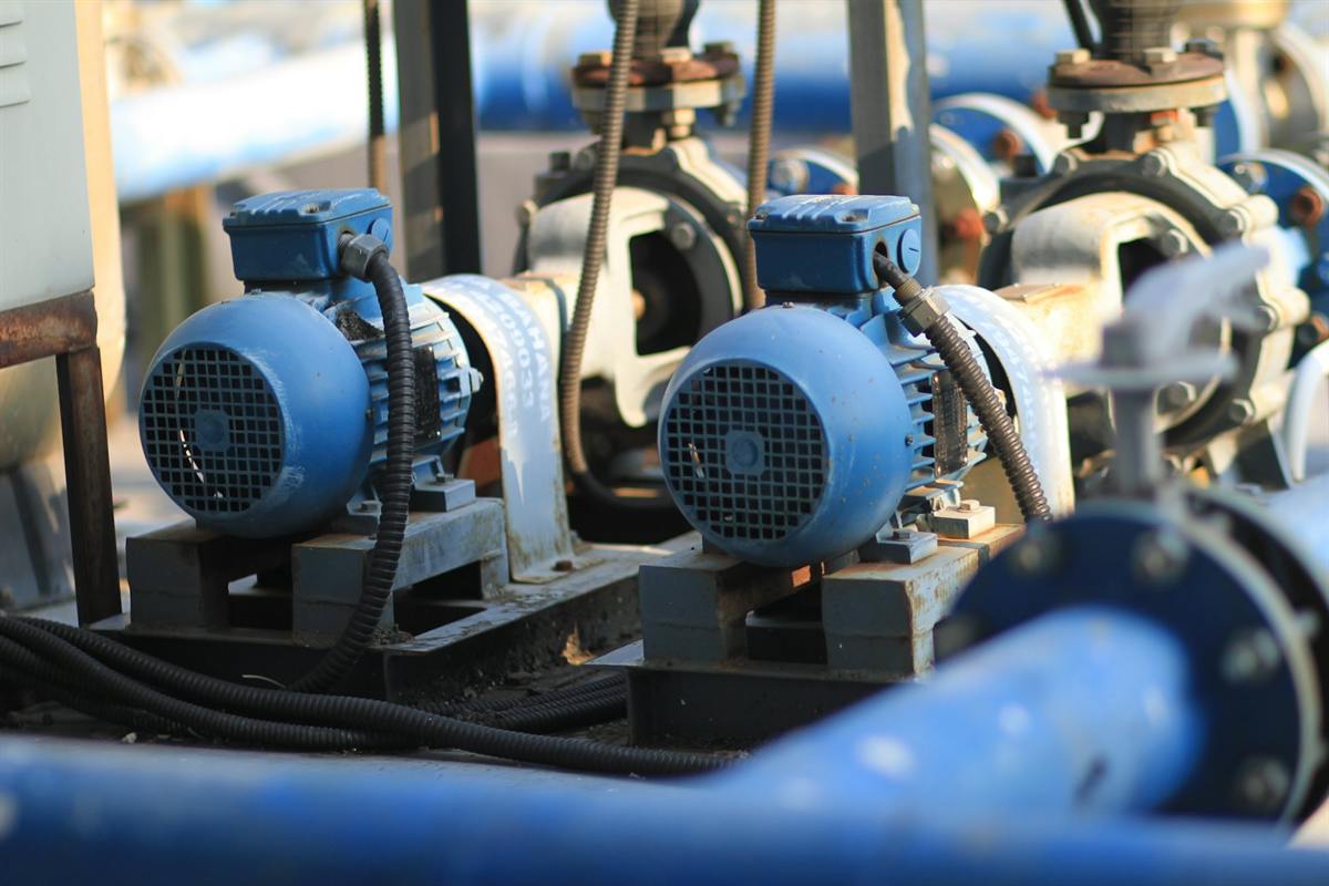 Row of blue electric motor-driven pumps connected to industrial pipework